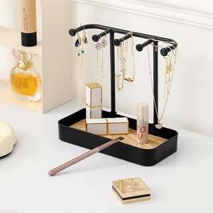 Black metal jewelry stand with hooks for necklaces and earrings on a wooden base tray