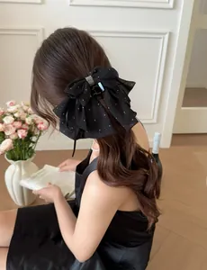 Detail of black chiffon bow hair claw with rhinestones and silver glitter on model hair