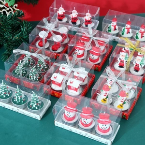 Christmas candle set with Santa and snowman in gift boxes on green festive background