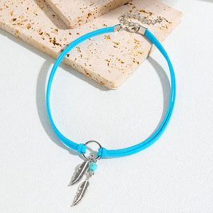 Detail of bohemian turquoise choker with silver feathers on a beige stone display