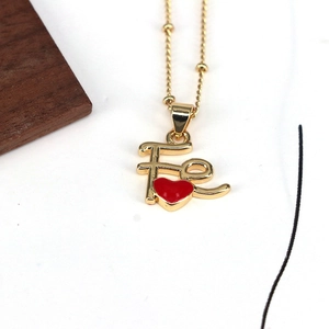 Golden bead chain necklace with Fe letter and red heart pendant on white background