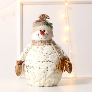 Plush Christmas snowman doll with gold knit hat and scarf in cozy home setting