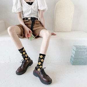 Detailed knit texture of black mid-calf socks with yellow smile face and SMILE text