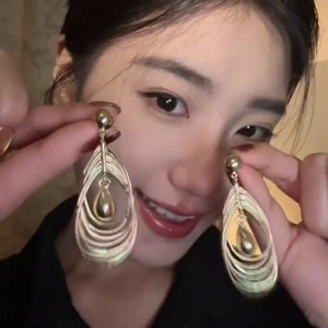 Golden multi-layer hollow teardrop tassel earrings worn by a model in a close-up shot