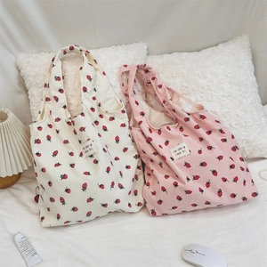 Gros plan de sacs cabas en velours côtelé à motif fraise en beige et rose avec étiquette