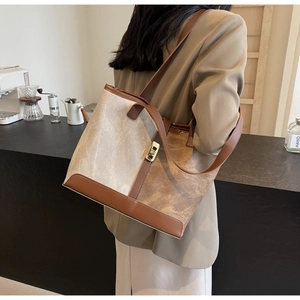 Detail of contrast color tote bag with brown leather strap and beige canvas texture