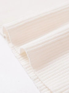 Close-up of premium white ribbed knit fabric showing soft texture and fine vertical stripes