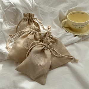 Close-up of small linen drawstring bags featuring minimalist embroidered smiley faces
