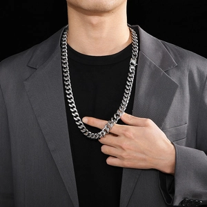 Detail shot of a 14mm silver-toned Cuban link chain worn by a male model with a grey blazer