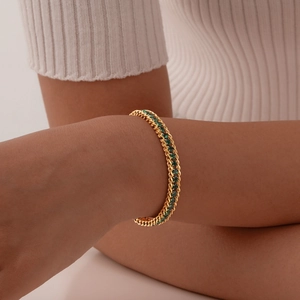 Elegant gold chain bracelet featuring vibrant green zircons worn on a model wrist