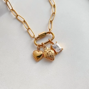 Detailopname van gouden rvs hangers met hart, aardbei en rechthoekige edelsteen