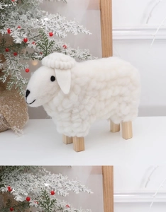 Close-up of white wool felt sheep ornament with natural wooden legs for Christmas decor