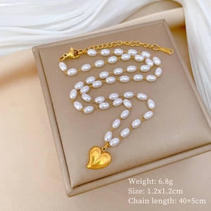 Detail view of gold heart pendant and white oval faux pearl necklace on display stand