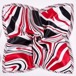 Macro view of silky texture and swirl pattern on red and black square neck scarf