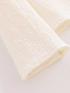 Detail shot of cream-white ruffled texture fabric and sleeve cuff on loose vacation set