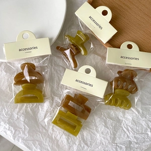 Solid jelly hair clips in brown and olive green on a white textured background