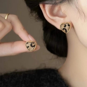 Detail eines herzförmigen Ohrrings mit Leopardenmuster und poliertem Goldmetallrand