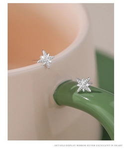 Macro shot of silver eight-point star earrings on a decorative ceramic cup edge