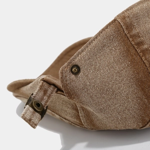 Macro detail of washed brown denim fabric with vintage copper snap button and stitching