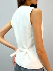 Detail of the white sleeveless vest featuring an adjustable back strap with a metal buckle