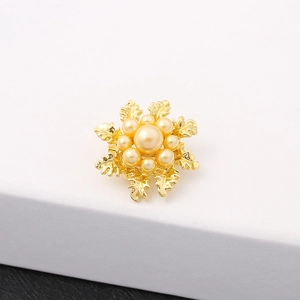 Elegant gold flower brooch with pearl cluster inlay on a white minimalist pedestal