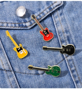 Detail of four colorful enamel guitar brooches pinned on blue denim fabric