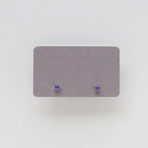 Detail of round cut purple stone stud earrings with a classic four-prong silver setting