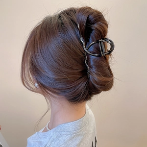 Detail view of the large glossy black wavy hair claw clip holding a high bun hairstyle