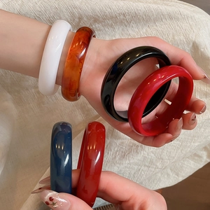 Detail showing various minimalist resin bangles in six colors on beige textured background