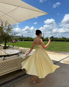 Back view of a yellow tube dress with lace-up details and a large flowing skirt