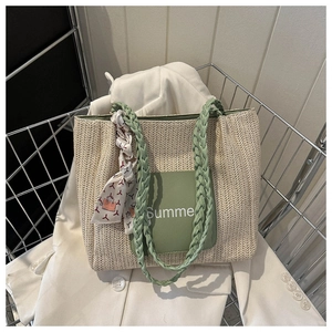 Détail du sac cabas en paille tissée avec patch Summer vert et foulard dans un panier