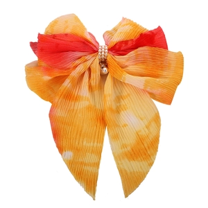 Detail of warm sunset tie-dye chiffon bow hair clip with luxury pearl beads decoration