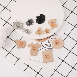 Close-up of various animal and creative alloy pins with butterfly clasps on a white plate