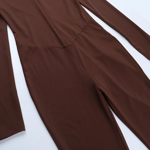 Detail of high-stretch brown knit fabric showing precision stitching on the flared jumpsuit