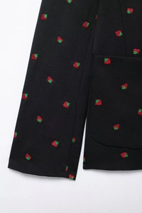 Détail de la broderie fraise sur la poche et les poignets d'un blazer noir
