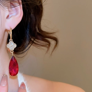 Detail of red water drop earrings with clover crystal studs on a female model