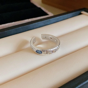 Macro shot of silver textured ring with blue zircon inlay in beige jewelry box