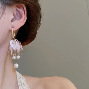 Detail of pink acrylic flower earrings with white pearl tassels on model's ear