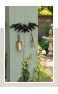 Detalle de gancho de pared de murciélago de hierro fundido con herramientas de jardín