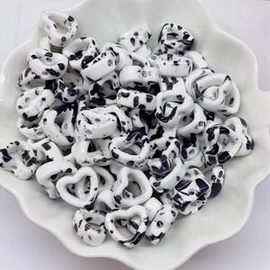 Macro shot of ink splatter pattern ceramic heart beads in a white flower shaped bowl