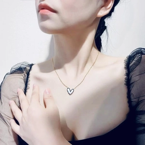 Close-up of golden titanium steel necklace with white heart enamel pendant on a model