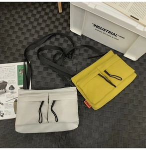 Nylon messenger bag featuring dual front pockets with drawstring and adjustable straps