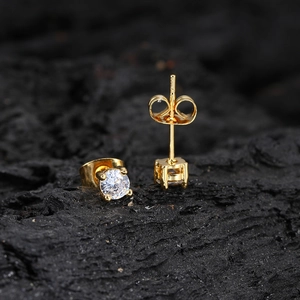 Elegant gold stud earrings with round clear zircon in four-prong setting on black texture