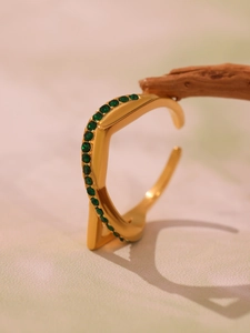 Detail of gold-plated open ring featuring a row of inlaid green zircon stones