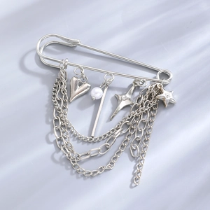Detailed view of silver safety pin brooch with heart charms and triple metal chains