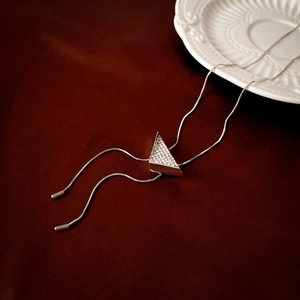 Macro shot of silver triangle pendant with white zircons on red velvet background