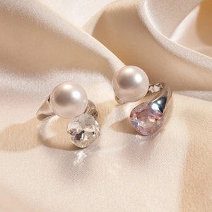 Detail of square glass crystals and white pearls on silver rings over champagne silk