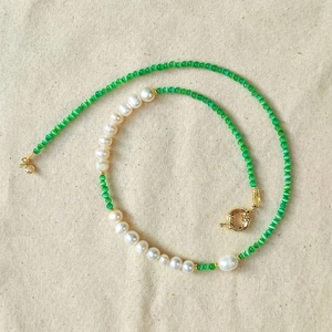 Detail of glacier blue cat eye stone beads and white pearls with golden sailor clasp necklace