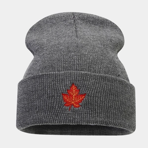 Close-up of red maple leaf embroidery on dark grey ribbed knit beanie hat