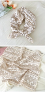 Detail of khaki geometric cotton scarf with lace edges tied in a bow over flat layout